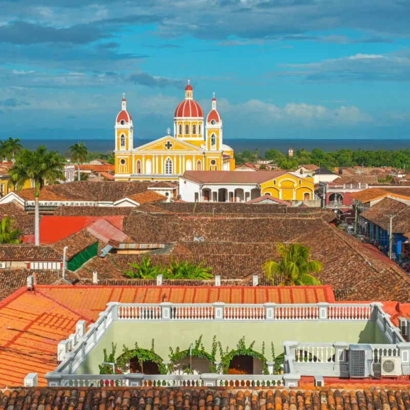 Urban skyline of Granada city at sunset with its spanish colonial architecture, colorful cathedral and beautiful rooftops with the Nicaragua Lake in the background, Nicaragua, Central America