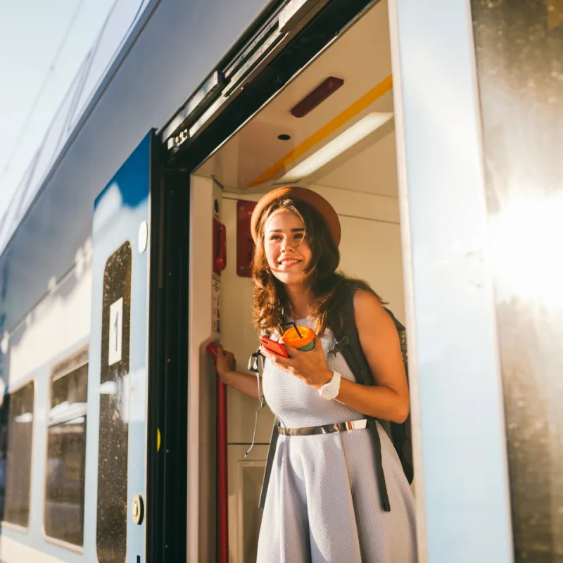 Woman peeking out train. Woman railway station. Young happy woman pulling face out train door looking for somebody railway station. Travelling. Portrait girl standing on train door when arrived