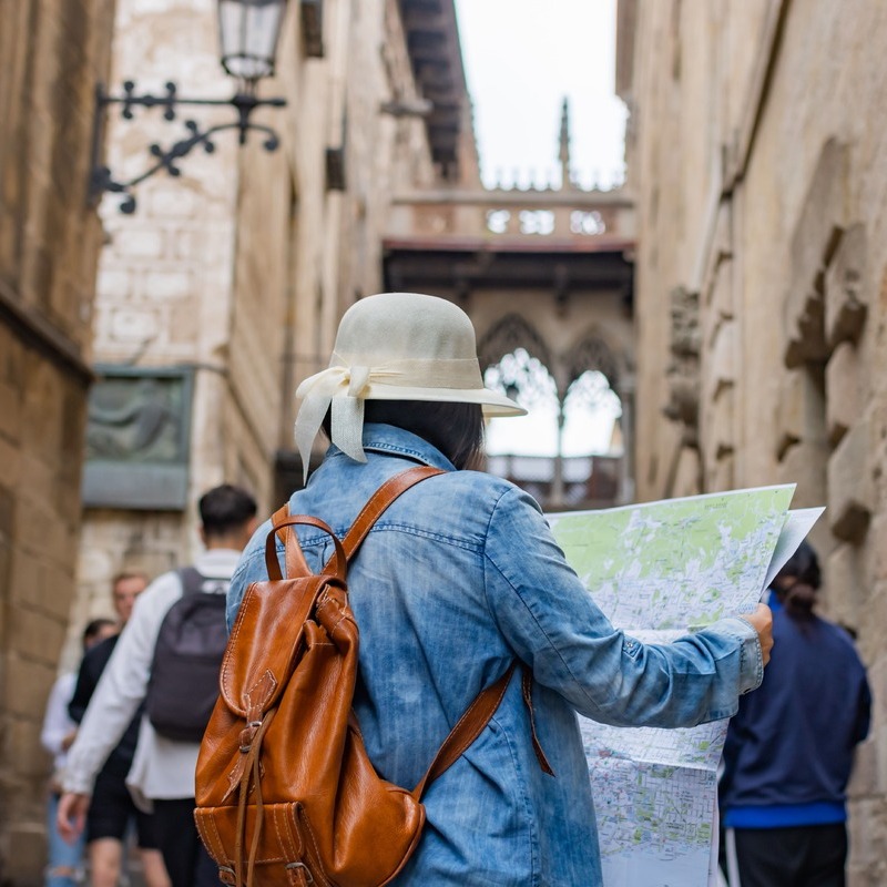 Female Tourist Reading Map While Exploring The Latin Quarter In Barcelona, Catalonia, Spain