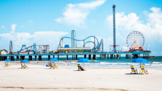 iew of beach umbrellas and Pleasure Pier amusement park on Galveston Island Texas