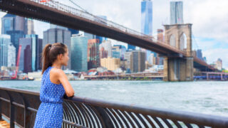 New York City woman looking at Brooklyn Bridge and view of downtown Manhattan skyline copy