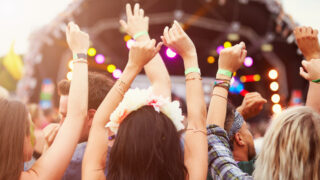 people at music festival hands up