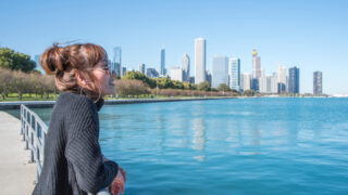 women standing in the City of Chicago downtown and she Walking around michigan lake at day time