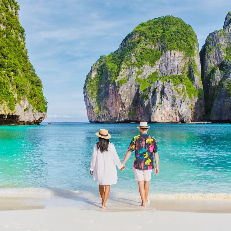A Couple Holding Hands As They Walk Into The Ocean On A Beach In Phuket, Thailand, Southeast Asia