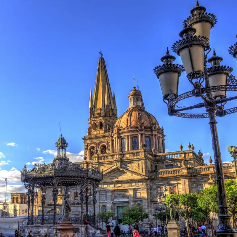 A view of the Guadalajara Cathedral across a plaza with a gazebo and people in the foreground