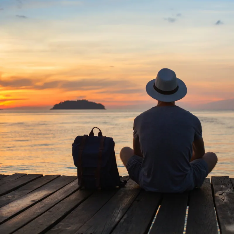 male solo traveler sitting on pier