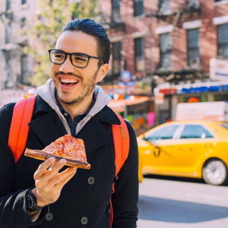man eating pizza in new york city