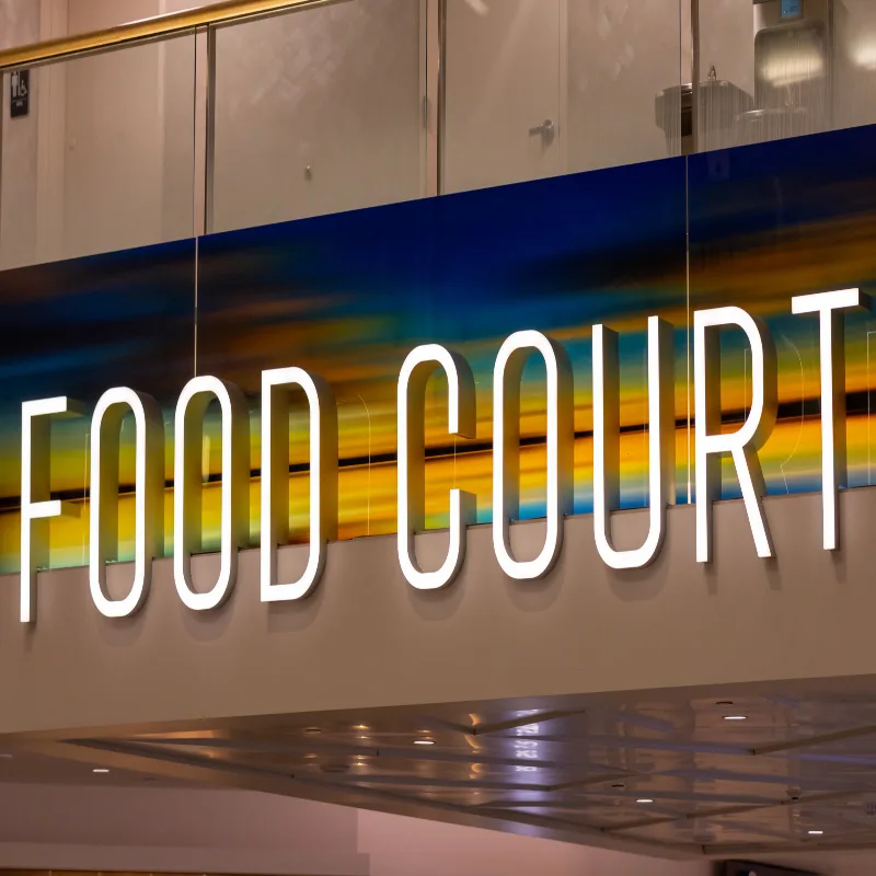 Neon sign read _Food Court_ above the hallway in the airport terminal