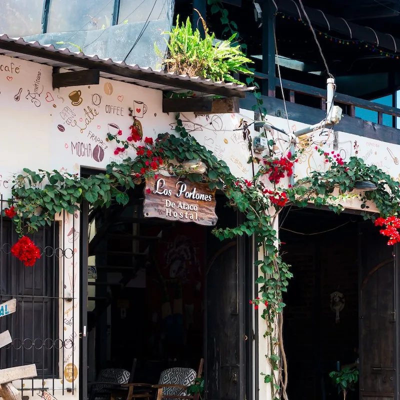 Facade of a hostel building along El Salvador's Ruta de las Flores with decorative wall and plants