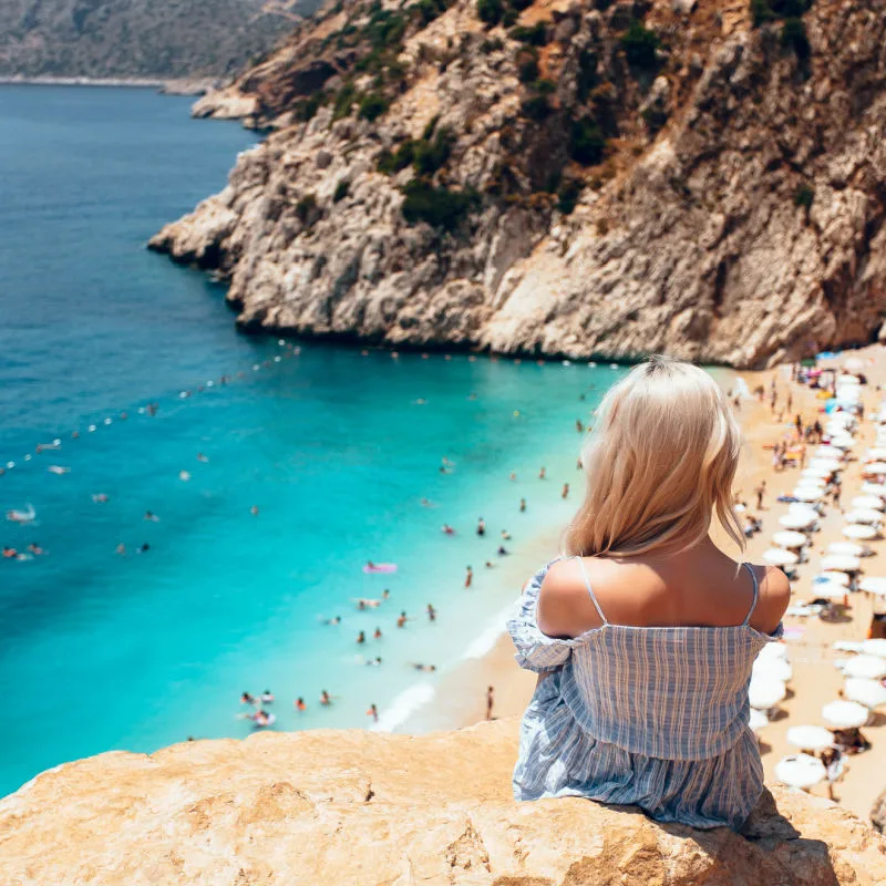 Woman At A Lookout Overlooking Kaputas Beach In Kas, Near Antalya, Turkiye, Eastern Mediterranean Coast