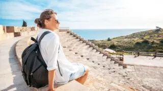Young Female Traveler Sitting On The Steps Of The Ancient Kourion Theatre, Near Limassol, Cyprus