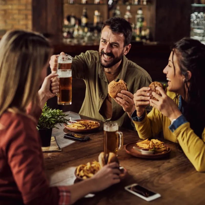 Young happy man toasting with friends while having lunch in a pub
