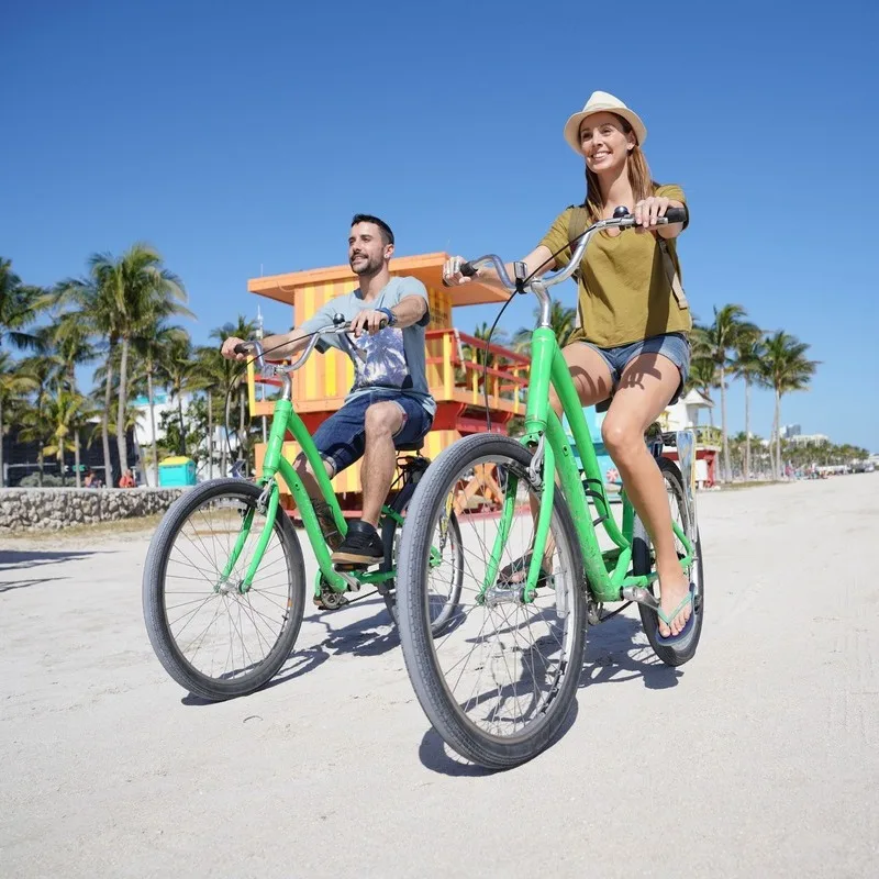 A couple rides bikes on the beach in Miami